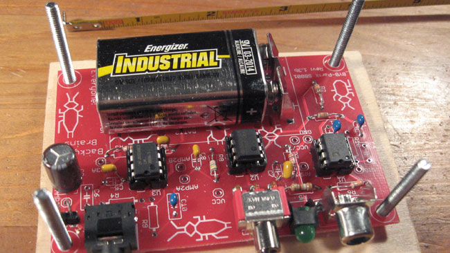 Place the four machine screws into the enclosure board without the speaker hole, turn the board over, and place the assembled PCB over the screws.